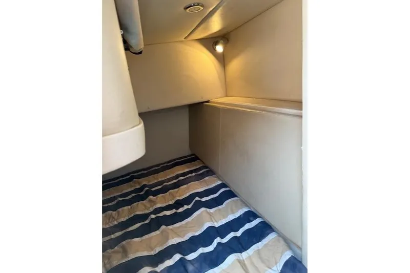 Slide: The Image of 2010 Bayliner 255 Cruiser cabin interior with striped bedding and soft lighting. - 34