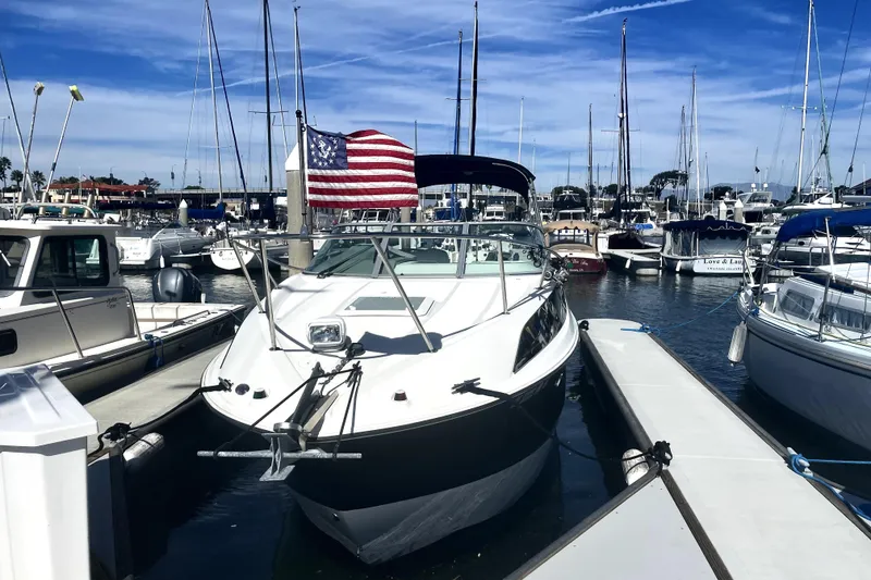Slide: The Image of 2010 Bayliner 255 Cruiser docked at marina with American flag, surrounded by sailboats. - 4