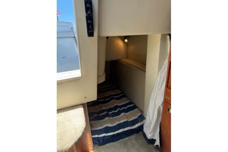 Slide: The Image of 2010 Bayliner 255 Cruiser cabin interior with striped bedding and cozy lighting. - 42