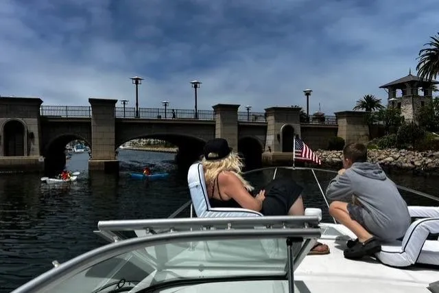 Slide: The Image of 2010 Bayliner 255 Cruiser on water near bridge, with people relaxing onboard. - 49