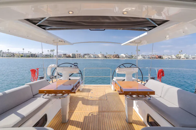 Slide: The Image of 2023 Beneteau Oceanis Yacht 60 deck with dual steering wheels and waterfront view. - 24