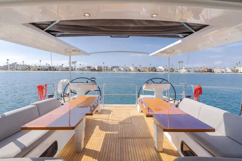 Slide: The Image of 2023 Beneteau Oceanis Yacht 60 deck with dual steering wheels and waterfront view. - 25