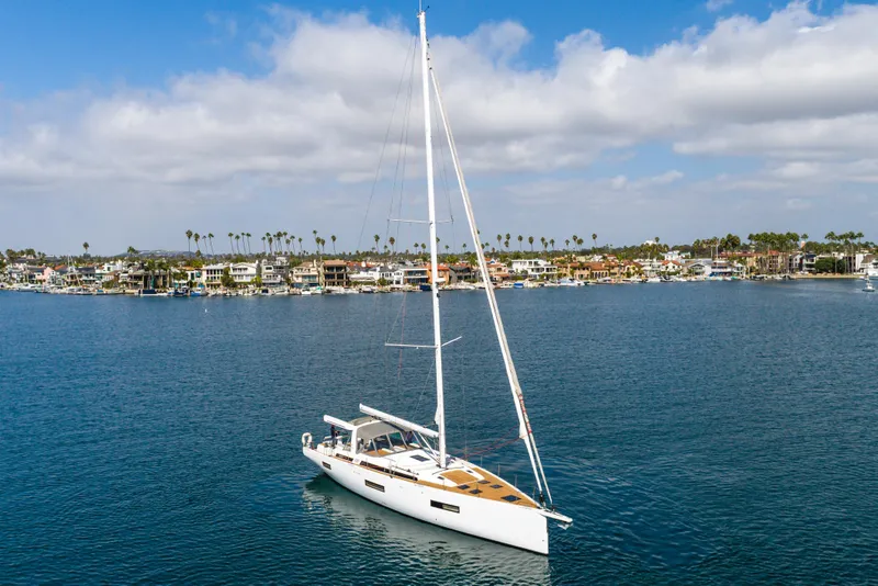 Slide: The Image of 2023 Beneteau Oceanis Yacht 60 sailing near coastal homes under a blue sky. - 47