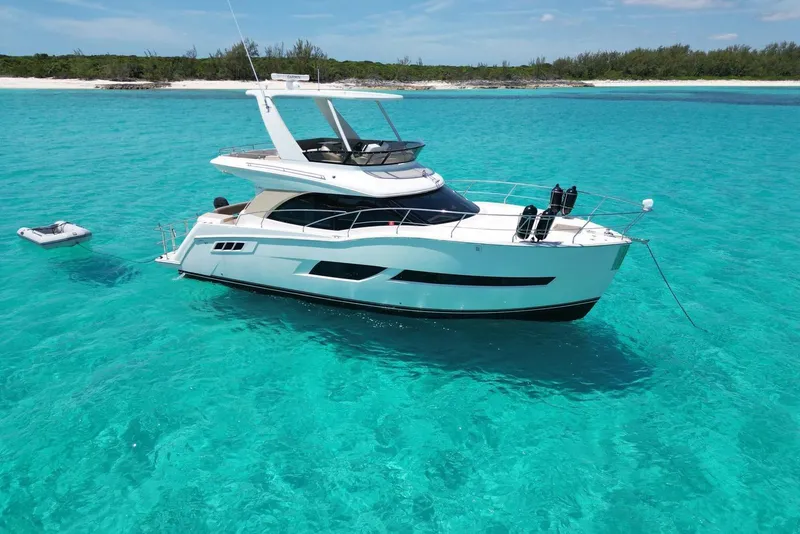 The Image of Luxurious 2017 Carver C40 yacht anchored in clear turquoise waters near a sandy beach. - 1