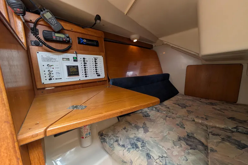 Slide: The Image of 2004 Catalina 310 yacht interior with navigation panel and cozy sleeping area. - 10
