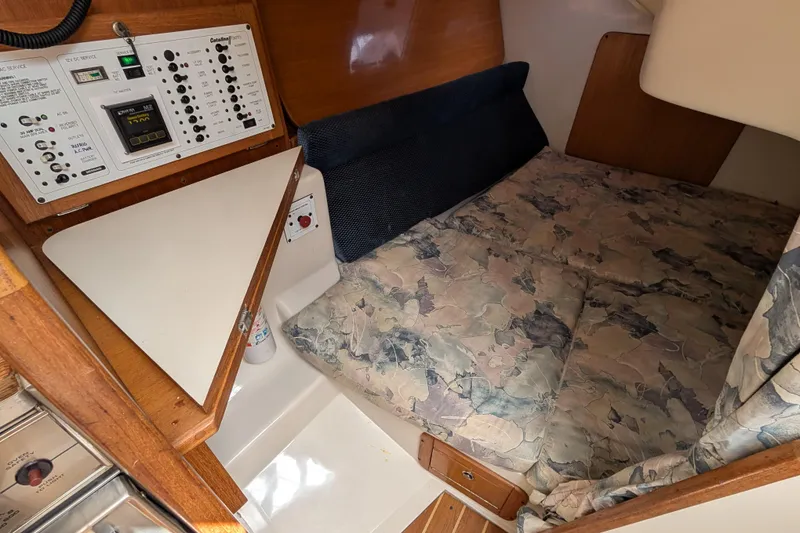 Slide: The Image of 2004 Catalina 310 yacht interior with control panel and cozy sleeping area. - 11