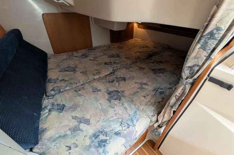 Slide: The Image of 2004 Catalina 310 cabin interior with floral-patterned bedding and wooden accents. - 12
