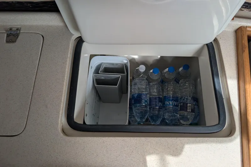 Slide: The Image of Storage compartment in a 2004 Catalina 310 sailboat with water bottles inside. - 13