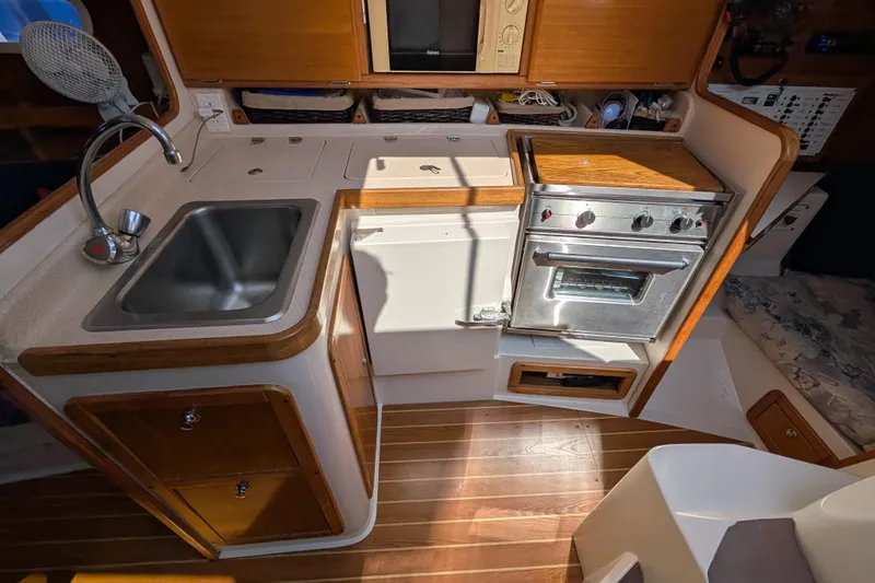 Slide: The Image of 2004 Catalina 310 yacht kitchen with sink, stove, and wooden cabinetry. - 4