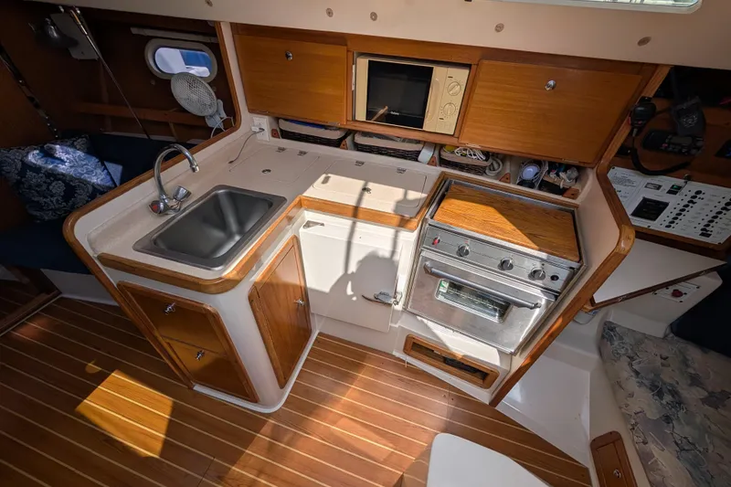 Slide: The Image of 2004 Catalina 310 yacht interior kitchen with sink, stove, and wooden cabinetry. - 5