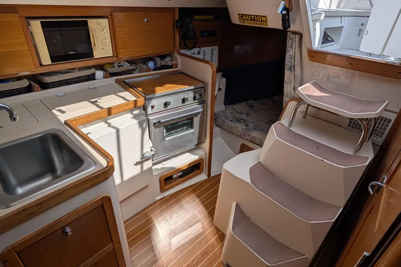 Slide: The Image of 2004 Catalina 310 yacht interior with kitchen, sink, stove, and steps leading to cabin. - 6