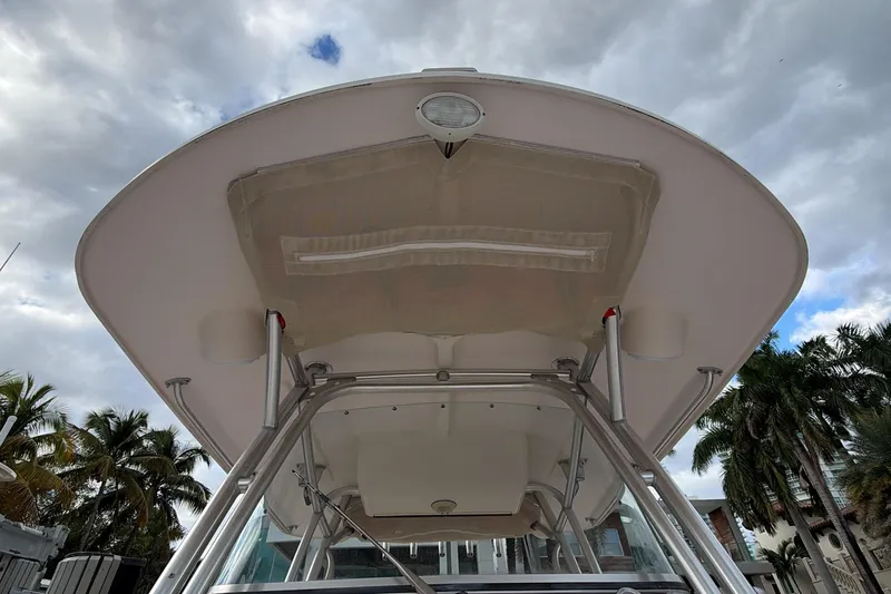 Slide: The Image of 2010 Grady-White Canyon 336 boat helm with rod holders, docked near modern buildings. - 30