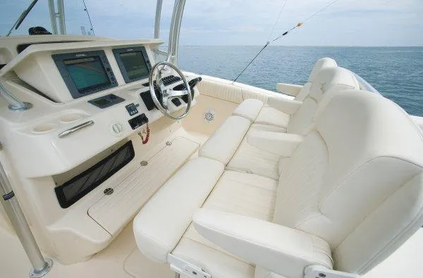 Slide: The Image of 2010 Grady-White Canyon 336 boat interior with white cushioned seating, docked near cityscape. - 5