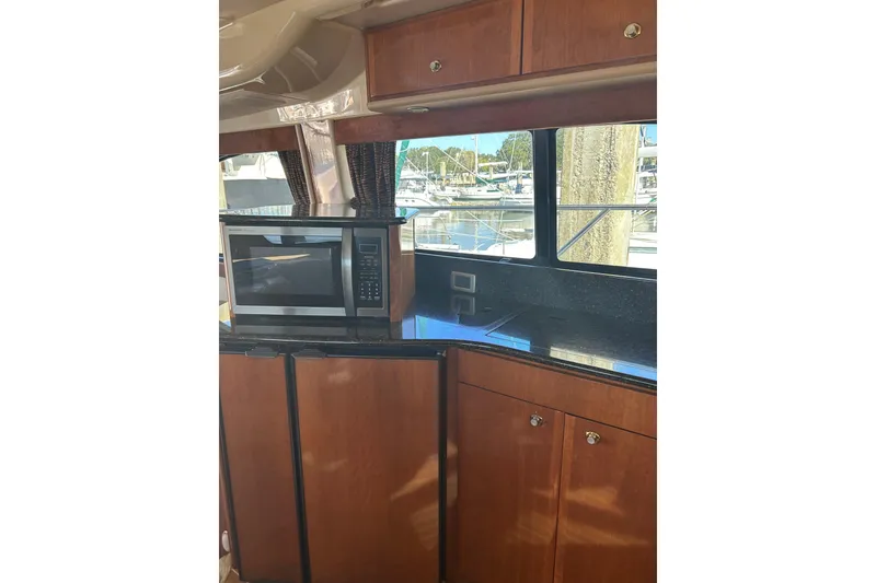 Slide: The Image of 2007 Meridian 411SB yacht kitchen with microwave, wooden cabinets, and marina view. - 53
