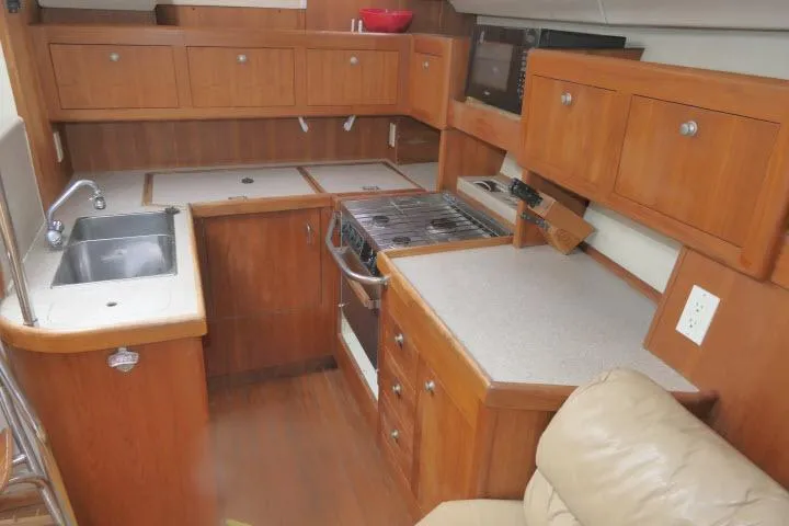 Slide: The Image of 1999 Hunter 450 Passage yacht kitchen with wooden cabinetry and modern appliances. - 12