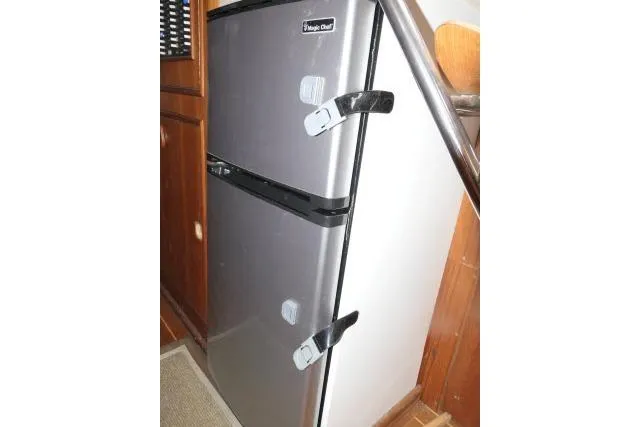 Slide: The Image of Compact fridge with safety latches inside a 1999 Hunter 450 Passage boat. - 21