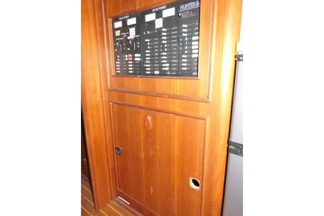 Slide: The Image of Electrical panel on 1999 Hunter 450 Passage yacht, featuring wooden cabinetry. - 23