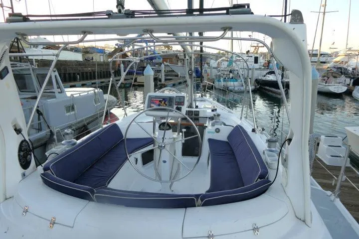 Slide: The Image of Cockpit of 1999 Hunter 450 Passage sailboat docked at marina, featuring steering wheel and seating. - 50