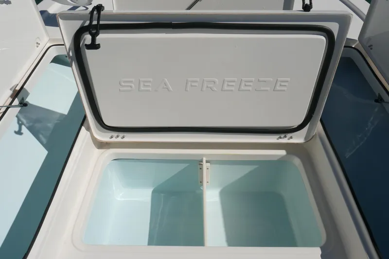 Slide: The Image of Open storage compartment on 2023 Sea Born FX24 Bay boat, labeled "Sea Freeze." - 11