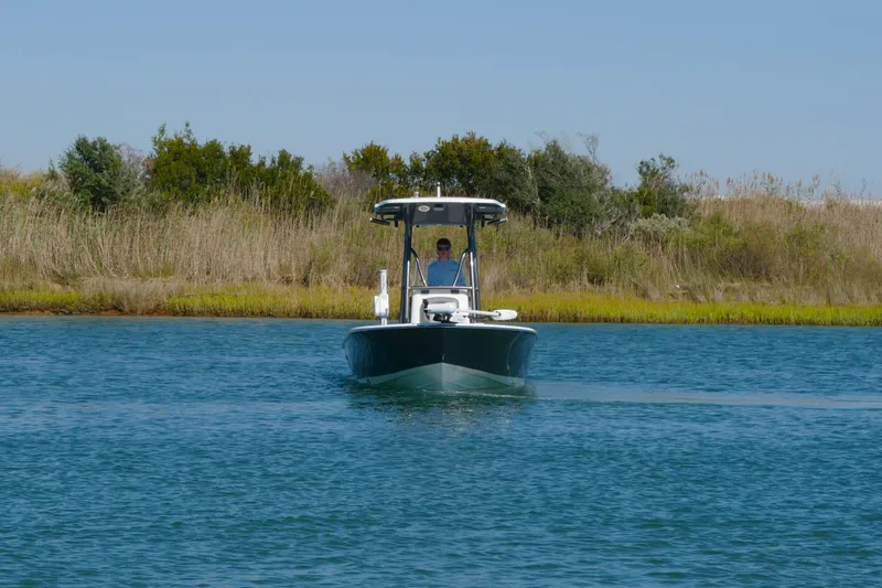 Slide: The Image of 2023 Sea Born FX24 Bay boat cruising on a calm waterway with grassy shoreline. - 2