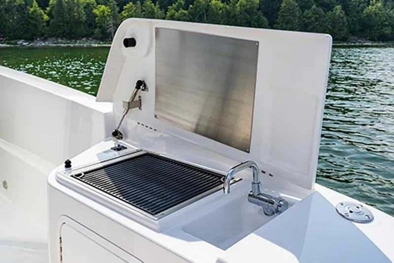 Slide: The Image of Outdoor kitchen on 2026 Cruisers Yachts 38 VTR, featuring grill and sink by a lake. - 17