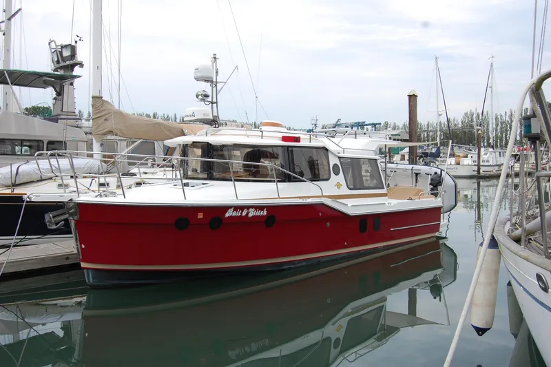 The Image of 2018 Ranger Tugs R29 boat docked in marina, featuring a red hull and white cabin. - 0
