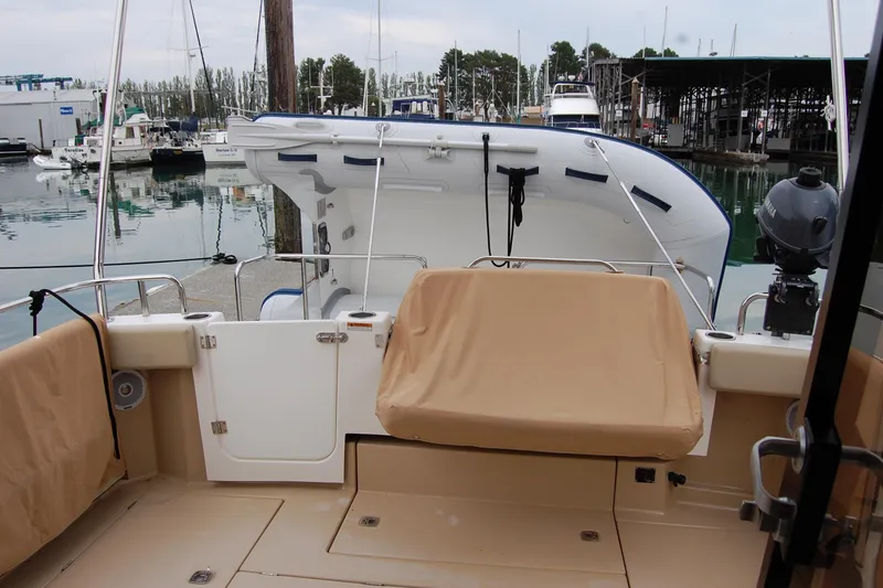 Slide: The Image of 2018 Ranger Tugs R29 boat interior with covered seating and docked view. - 12