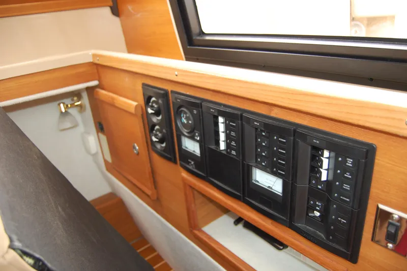 Slide: The Image of 2018 Ranger Tugs R29 interior control panel with wood finish and switches. - 13
