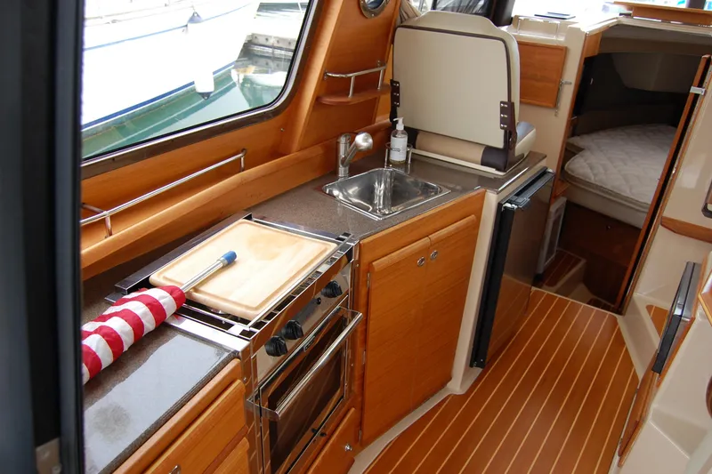 Slide: The Image of 2018 Ranger Tugs R29 interior kitchen with wood cabinetry and compact appliances. - 16