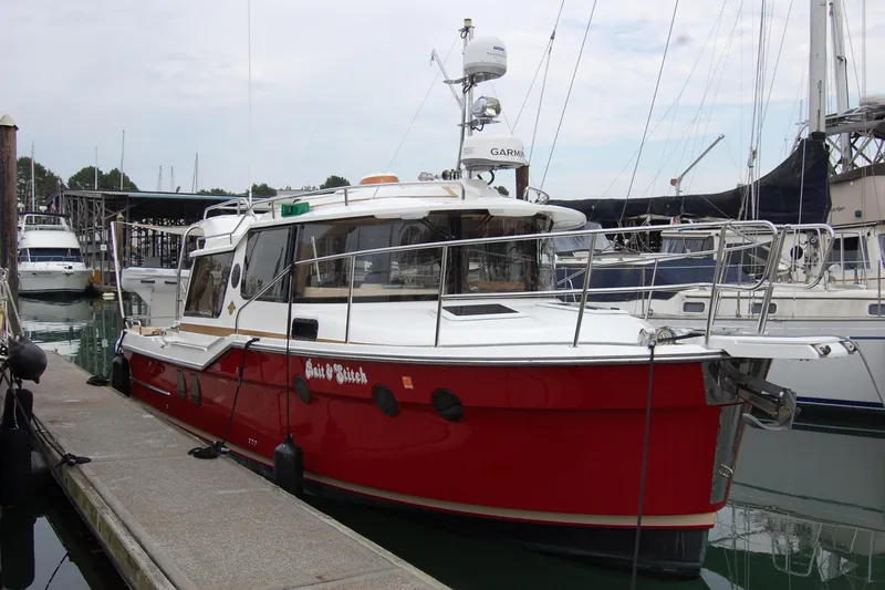 Slide: The Image of 2018 Ranger Tugs R29 boat docked in marina, featuring red hull and white cabin. - 2