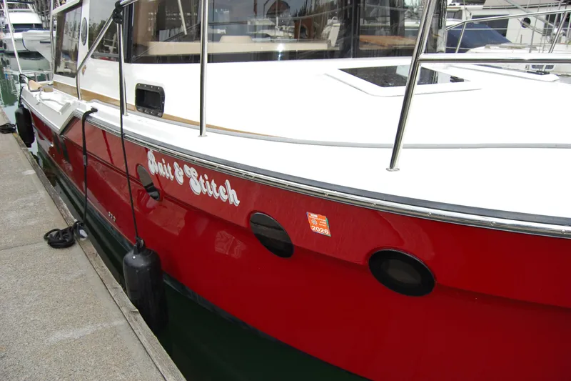 Slide: The Image of 2018 Ranger Tugs R29 boat docked, featuring a red hull and white deck. - 3