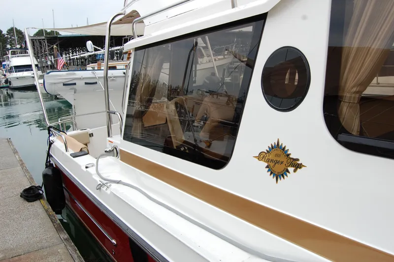 Slide: The Image of 2018 Ranger Tugs R29 boat docked at marina, side view with logo visible. - 6