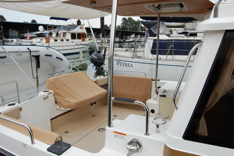 Slide: The Image of 2018 Ranger Tugs R29 boat interior at marina, featuring covered seating and docked vessels. - 7
