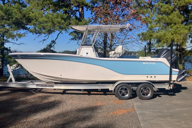 The Image of 2024 Sea Fox 248 Commander boat on trailer, parked near a lake with trees. - 0