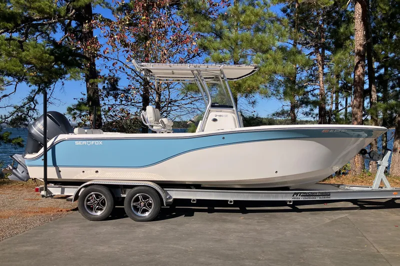 Slide: The Image of 2024 Sea Fox 248 Commander boat on trailer, parked near a lake with trees. - 4