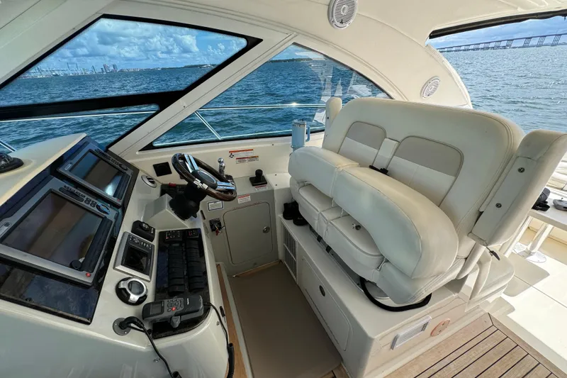 Slide: The Image of 2011 Sea Ray 470 Sundancer helm with dual seats and navigation controls, overlooking ocean. - 47