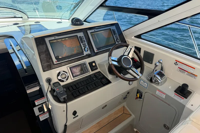 Slide: The Image of 2011 Sea Ray 470 Sundancer helm with navigation screens and steering wheel. - 52