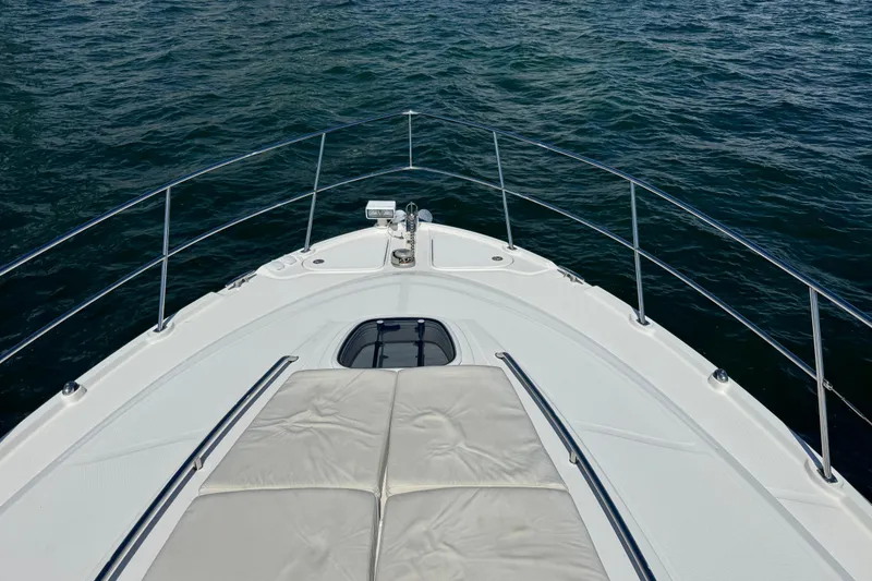 Slide: The Image of 2011 Sea Ray 470 Sundancer yacht bow with sunpad, overlooking calm ocean waters. - 63
