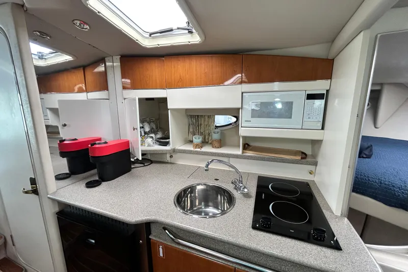Slide: The Image of Galley with sink, electric stove, microwave, and storage cabinets. - 14
