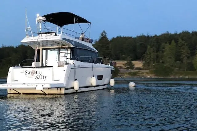 Slide: The Image of 2018 Jeanneau Velasco 37F yacht on calm water, surrounded by trees. - 21