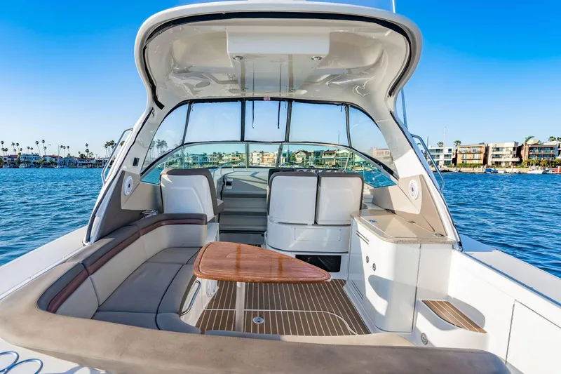 Slide: The Image of 2016 Sea Ray 370 Express Cruiser interior with seating and table on calm water. - 15