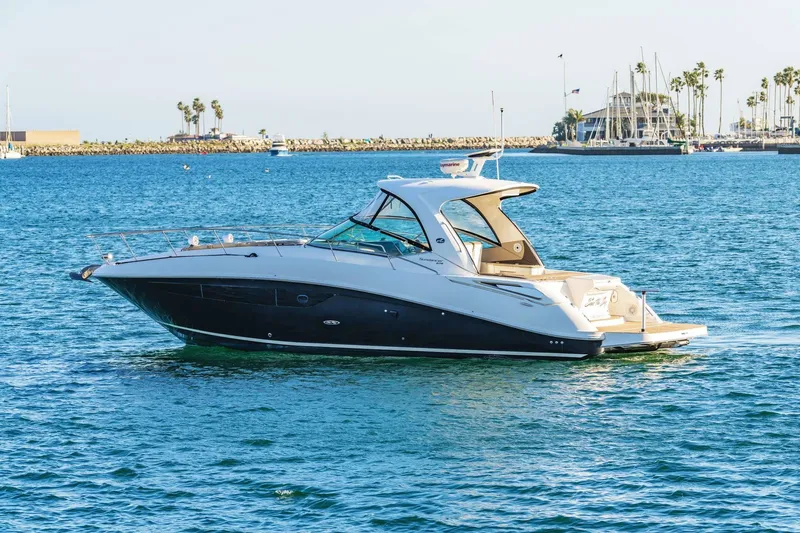Slide: The Image of 2016 Sea Ray 370 Express Cruiser on calm blue waters near a marina. - 4