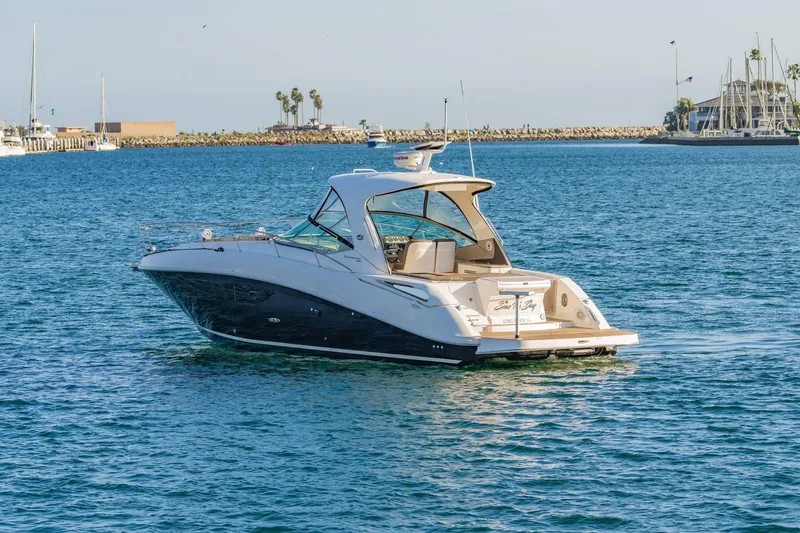 Slide: The Image of 2016 Sea Ray 370 Express Cruiser on calm waters, scenic marina backdrop. - 5