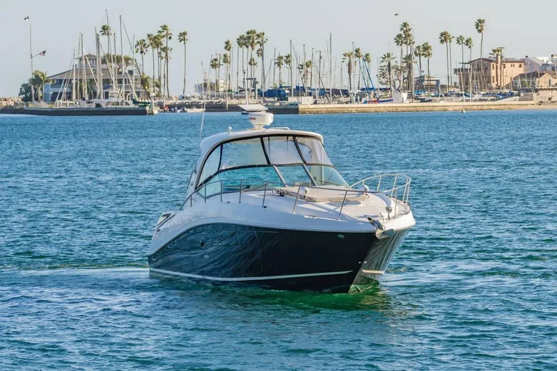 Slide: The Image of 2016 Sea Ray 370 Express Cruiser on calm waters near a marina with palm trees. - 2