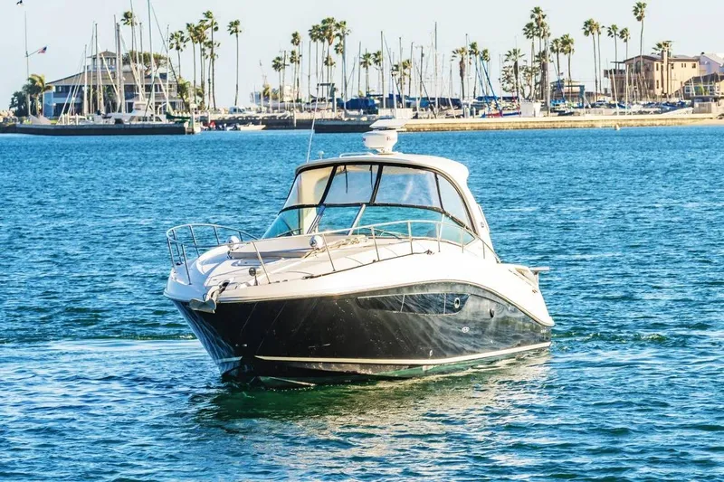 Slide: The Image of 2016 Sea Ray 370 Express Cruiser on blue water near marina with palm trees. - 3