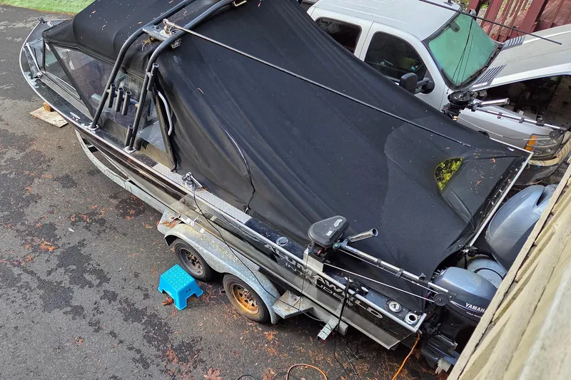 Slide: The Image of 2008 Alumaweld 22 Intruder boat covered, parked on trailer beside vehicles. - 3