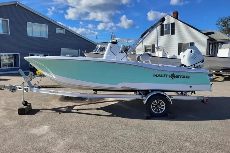 The Image of 2025 NauticStar 191 Hybrid boat on trailer, parked outdoors under a clear blue sky. - 1