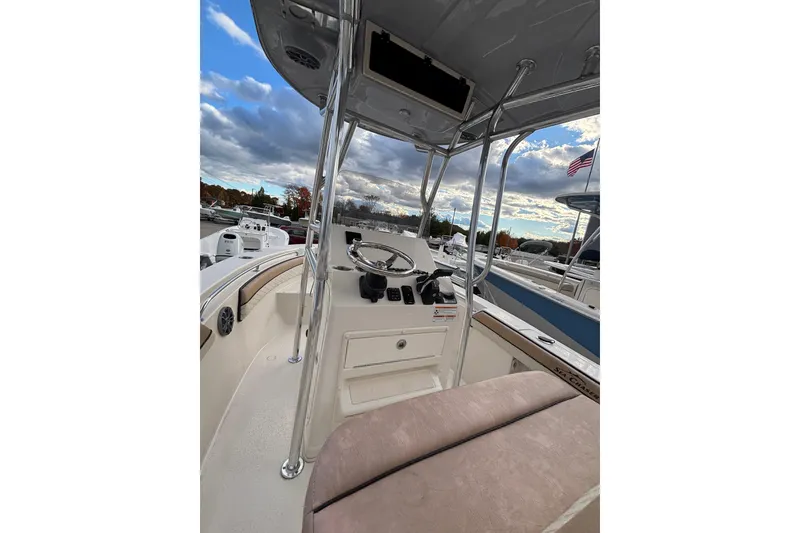 Slide: The Image of 2023 Sea Chaser 20 HFC boat interior with steering console and seating, docked under cloudy sky. - 3