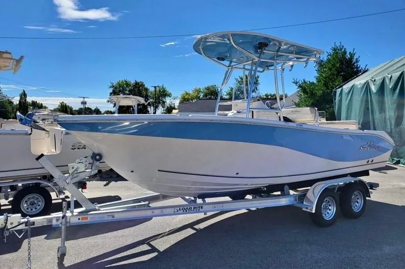 The Image of 2023 Sea Chaser 22 HFC boat on trailer, blue and white design, sunny day. - 1