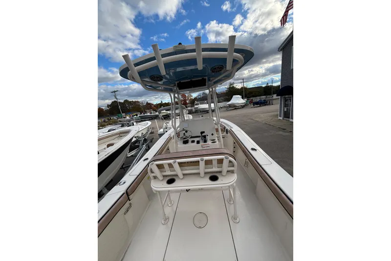 Slide: The Image of 2023 Sea Chaser 24 HFC boat interior with T-top and rod holders, docked under cloudy sky. - 8